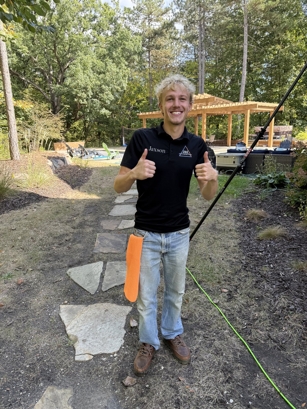 Jaxson P., co-founder of JBL Exterior Pros, in a branded polo holding a water-fed pole